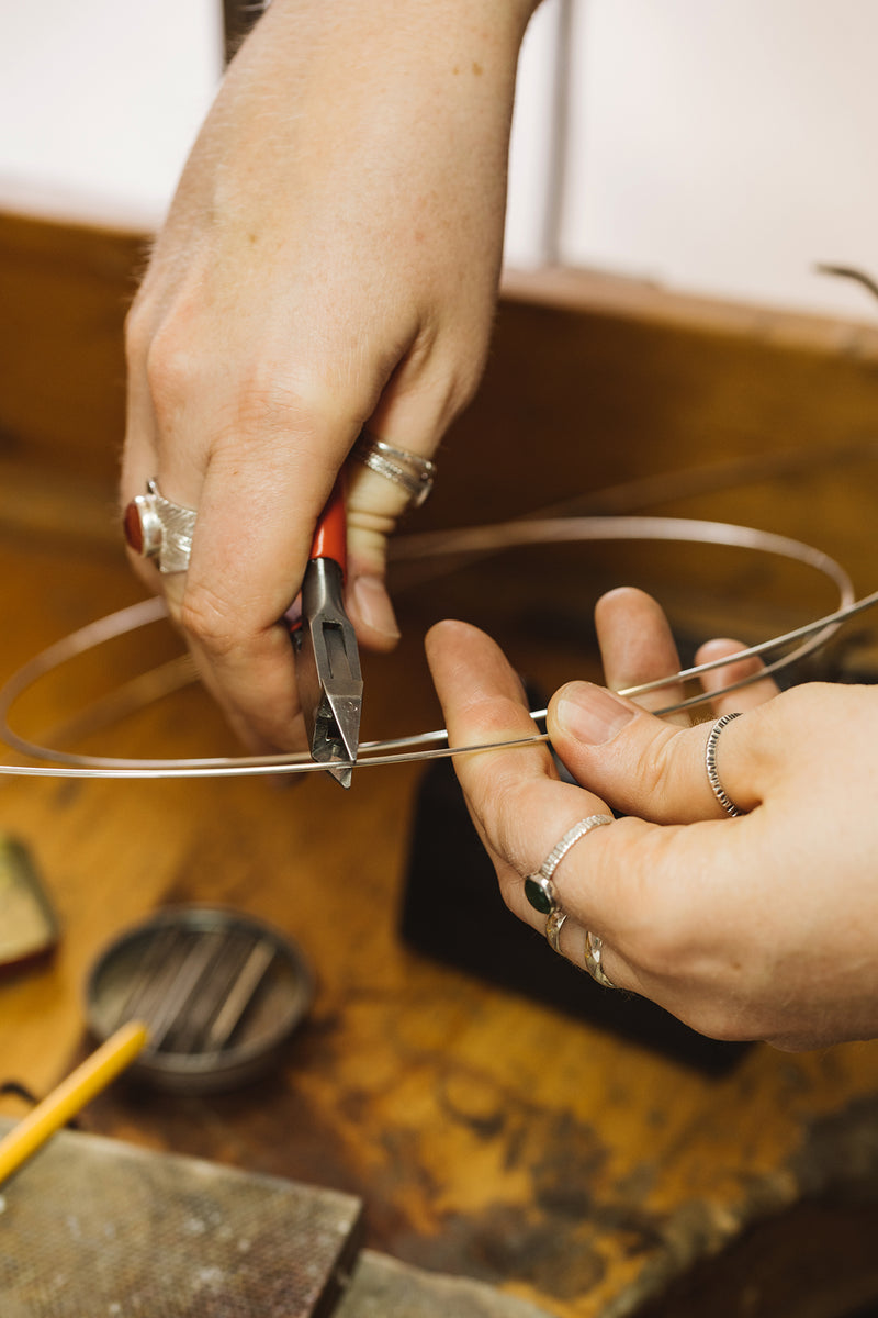 Artisan Jeweler in her studio cutting silver wire to make earrings